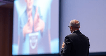 professional conference speaker on stage with presentation screen